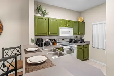 a kitchen with green cabinets and a sink at Peaceful Palms Stay for 6 in Kissimmee