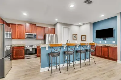 a kitchen with wooden cabinets and a blue island with bar stools at 7668 Wilmington Loop in Orlando
