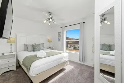 a white bedroom with a bed and a mirror at Freshly Updated Near Disney Private Pool Resort in Kissimmee