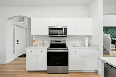 a kitchen with white cabinets and a black stove top oven at Freshly Updated Near Disney Private Pool Resort in Kissimmee