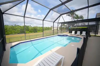 a large swimming pool with chairs and a large glass building at 6BR Family Vacation Home near Disney in Kissimmee