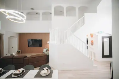 a living room with a couch and a staircase at 6BR Family Vacation Home near Disney in Kissimmee