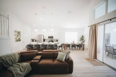 a living room with a brown couch and a kitchen at 6BR Family Vacation Home near Disney in Kissimmee
