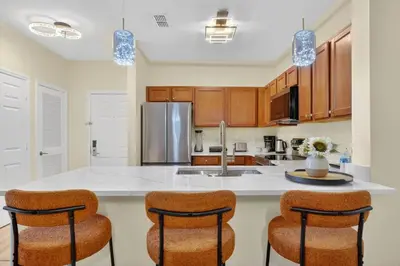 a kitchen with a white counter top and chairs at 3176-205 Resort Pool Condo Apt near Disney in Kissimmee