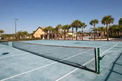 a tennis net on a tennis court with palm trees at Townhouse 4Q c/ Piscina no Paradise Palms in Kissimmee