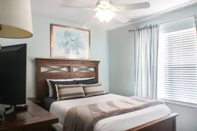 a bedroom with a bed and a tv and a window at Family Private Home W Heated Pool 12Min To Walt Disney in Kissimmee