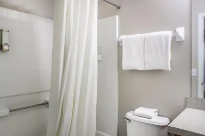 a bathroom with a toilet and a shower with towels at Family Private Home W Heated Pool 12Min To Walt Disney in Kissimmee