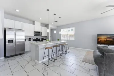 a kitchen with white cabinets and bar stools at Savvy 4Bed Stay Near Orlando Attractions in Kissimmee