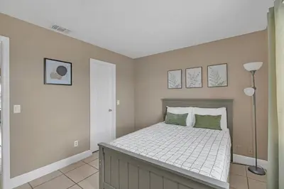 a bedroom with a bed with white sheets and green pillows at Lakefront Home Game Room & Views in Kissimmee