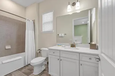 a white bathroom with a toilet and a sink at Blush Breeze Cottage Near Disney With Private Pool & Margaritaville Resort And Island H20 Waterpark Access - 2940Sr in Orlando