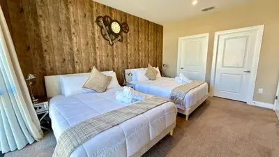 a bedroom with two beds and a clock on the wall at Magic Villa - 4 En-Suite & BBQ Grill in Orlando