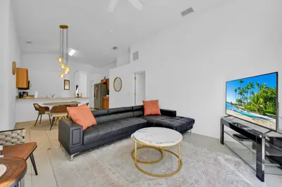 a living room with a black couch and a tv at Spacious Emerald Home with Pool Lanai Near Disney in Kissimmee