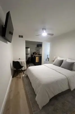 a white bedroom with a large bed and a desk at Cozy Ground Floor Studio Near Disney in Kissimmee