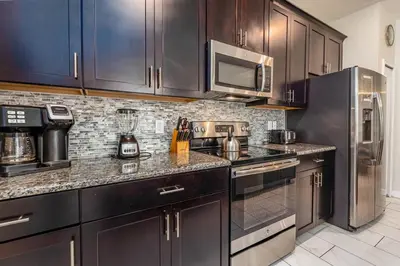 a kitchen with black cabinets and stainless steel appliances at 4BR Townhome w Pool in Storey Lake - Near Disney in Kissimmee