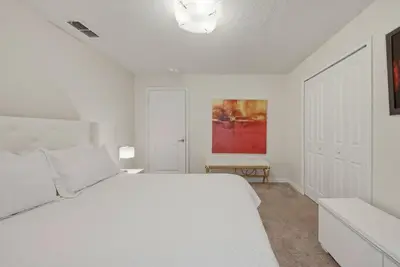 a white bedroom with a white bed and a painting at Cozy 5 Bedrooms and 4 Bathrooms At Storey Lake in Kissimmee