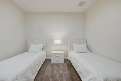 two beds in a white room with a lamp on a night stand at Cozy 5 Bedrooms and 4 Bathrooms At Storey Lake in Kissimmee