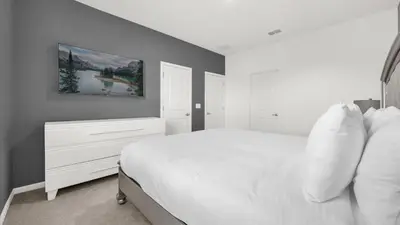 a bedroom with a white bed and a painting on the wall at Upstay Spacious Villa w Pool, Hot Tub & Game Room in Kissimmee