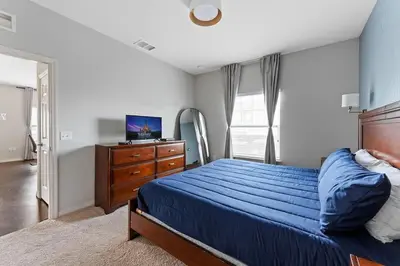 a bedroom with a bed and a dresser and a television at Townhome 4Q Temático — 15min da Disney in Kissimmee