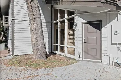 a tree in front of a house with a door at Romantic Getaway Cabin with Jacuzzi in Kissimmee