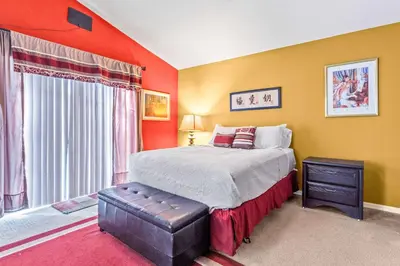 a bedroom with orange walls and a bed and a window at The Art House Home for 8 in Orlando