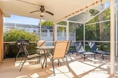 a screened in porch with chairs and a table at The Art House Home for 8 in Orlando