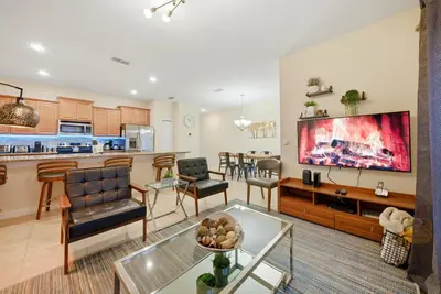 a living room and kitchen with a large screen tv at Cozy Home Luxury 04 Bedrooms At Storey Lake in Kissimmee