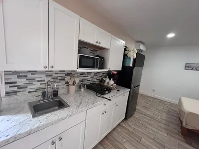 a kitchen with white cabinets and a sink and a refrigerator at Private Guesthouse in Orlando