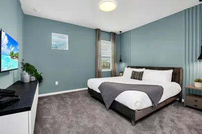 a bedroom with a large bed with blue walls at Luxurious 15-Bedroom Villa With Pool & Games Room in Kissimmee