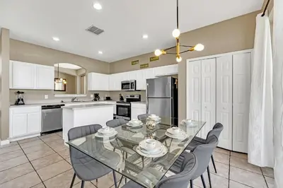 a kitchen and dining room with a glass table and chairs at Luxury 8-Bed Villa Near Disney With Pool & More in Kissimmee