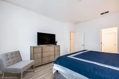a bedroom with a bed and a tv and a chair at Ev2619 - Sonoma Retreat in Kissimmee