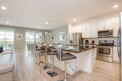 a kitchen with white cabinets and a bar with stools at Ev2619 - Sonoma Retreat in Kissimmee