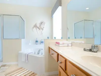 a bathroom with a sink and a tub and a mirror at Ev2753 - Golden Horizon Villa in Kissimmee