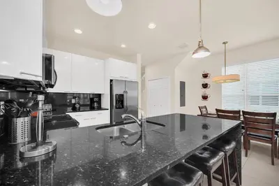 a kitchen with a black counter top and chairs at Ev1447 - The Retreat Villa in Orlando