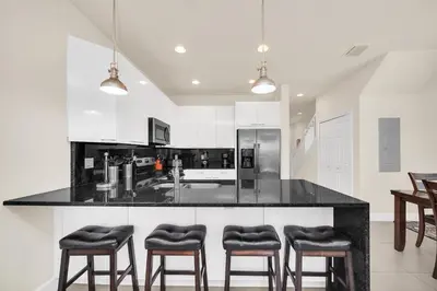 a kitchen with a black counter and four stools at Ev1447 - The Retreat Villa in Orlando