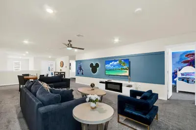 a living room with blue furniture and a large screen tv at Ev2010 - Windsor Star Retreat in Kissimmee