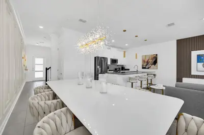 a white kitchen with a long white table and chairs at Ev2444 - Palm Breeze Escape in Kissimmee