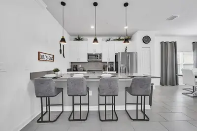 a kitchen with a island with chairs and a counter top at Ev2529 - Grand Orchid Retreat in Kissimmee