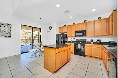 a kitchen with wooden cabinets and black counter tops at Ev2628 - Veranda Palms Hideaway in Kissimmee
