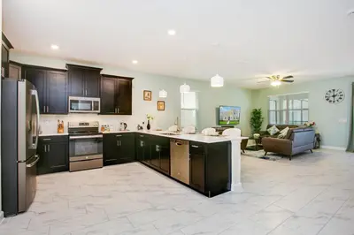 a kitchen with black cabinets and a living room at Ev2709 - Enchanted Retreat Villa in Kissimmee