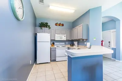 a kitchen with blue walls and a white refrigerator at Ev2739 - Emerald Serenity Villa in Kissimmee