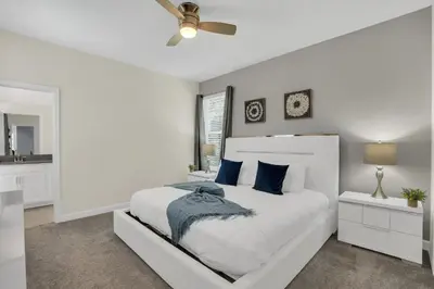 a white bedroom with a large bed with blue pillows at Ev2775 - Majestic Escape Villa in Kissimmee
