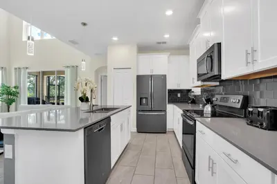 a kitchen with white cabinets and stainless steel appliances at Ev2775 - Majestic Escape Villa in Kissimmee