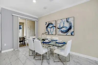 a dining room with a glass table and white chairs at Ev2861 - Sunshine Grove Villa in Kissimmee