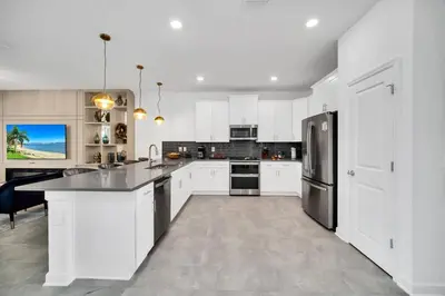 a kitchen with white cabinets and a stainless steel refrigerator at Ev2900 - Sunset Cove Retreat in Kissimmee