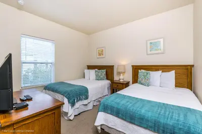 a bedroom with two beds and a tv and a desk at Ev014 - Lucaya Retreat in Kissimmee