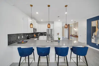a kitchen with blue chairs and a large island at Ev2989 - Serenity Palms Villa in Kissimmee