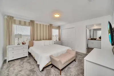 a white bedroom with a large bed and a chair at Ev3007 - Lakeside Escape Villa in Kissimmee