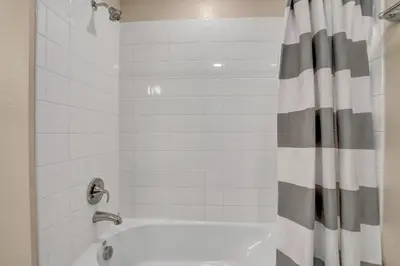 a bathroom with a tub with a shower curtain at Ev101 - The Luxe Loft in Kissimmee