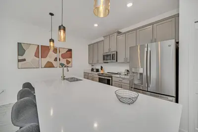 a white kitchen with a large white table and appliances at Ev4228 - Storey Retreat in Kissimmee