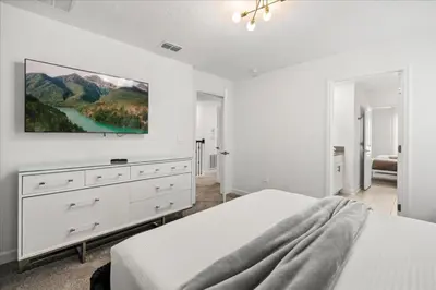 a white bedroom with a bed and a dresser at 4324Prolouge in Kissimmee